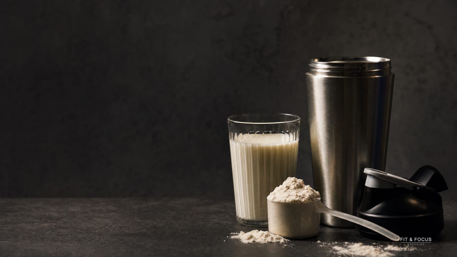 Open shakerbeker, een schep eiwitpoeder en een glas melk