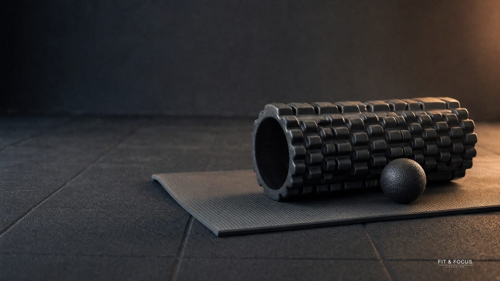 Foamroller op een uitgerolde matje met een massagebal ernaast