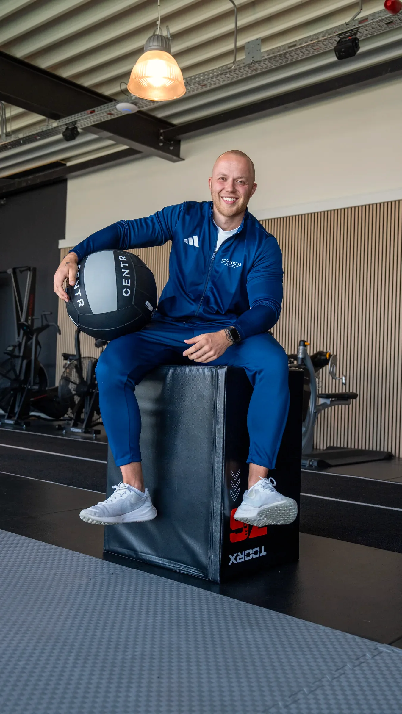 Coach Job de Boer zittend op een plyobox met medicijnbal