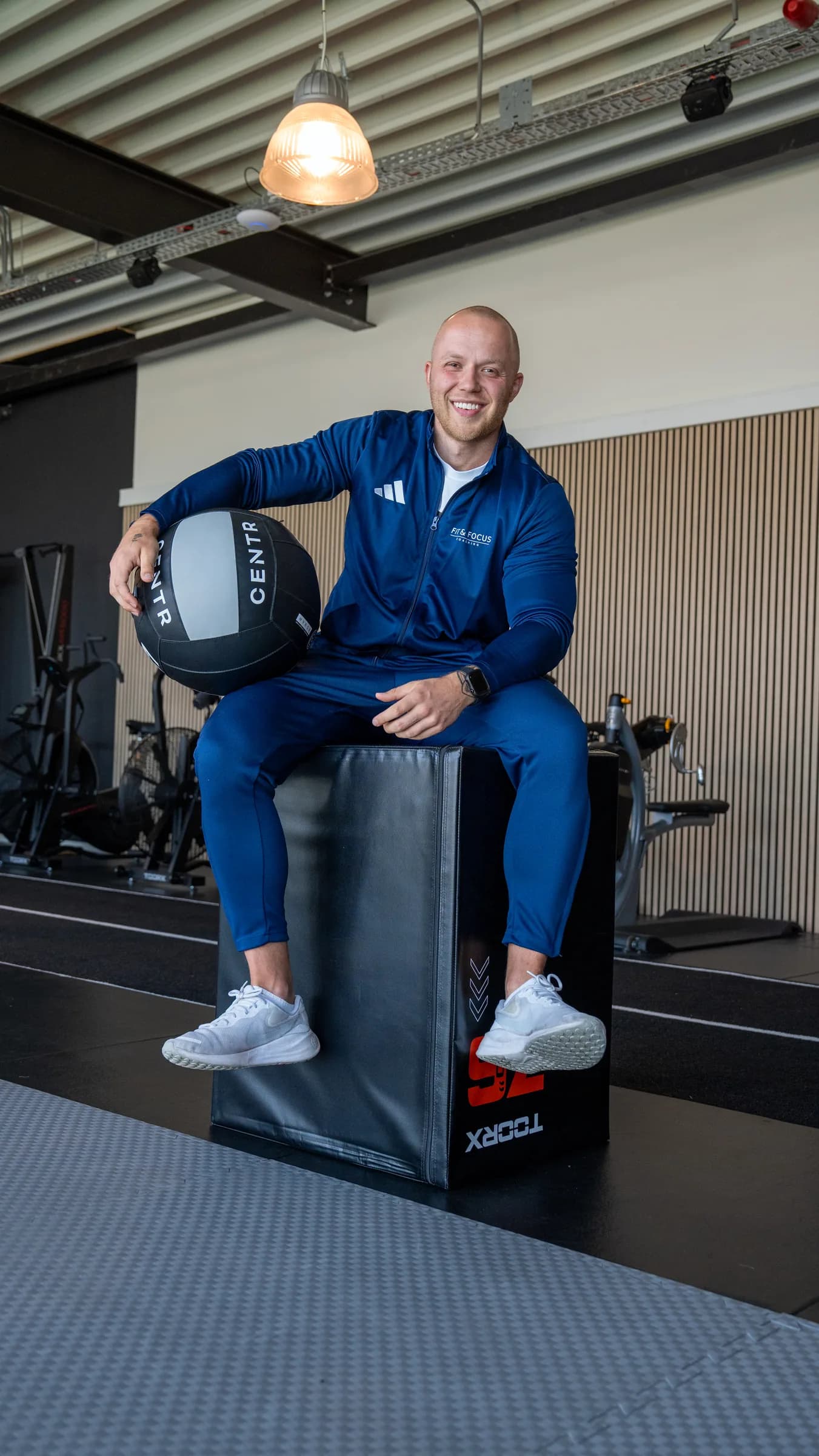 Coach Job de Boer zittend op een plyobox met medicijnbal