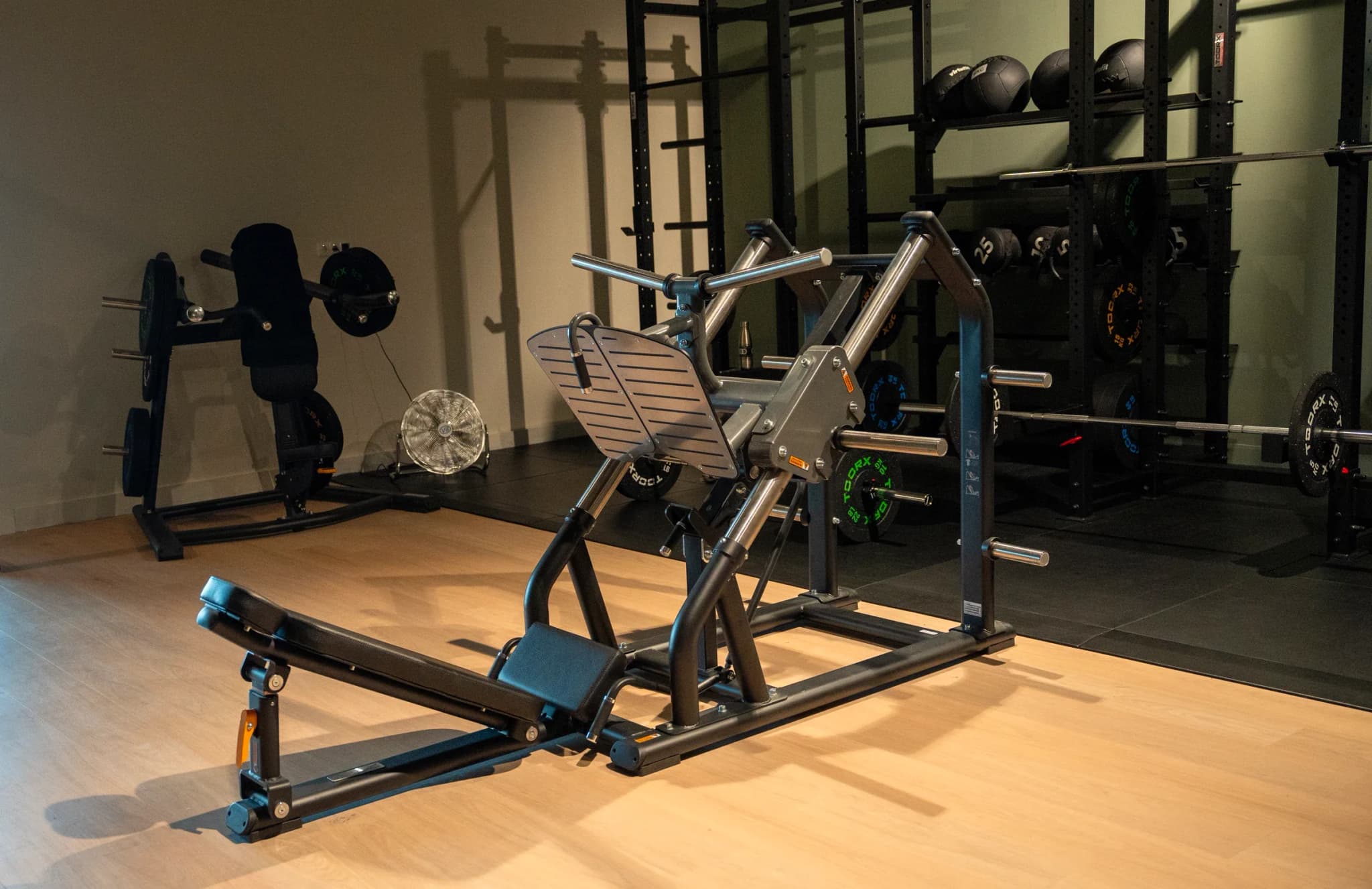 Verticale legpress op de houten vloer, met schijvenrekken erachter